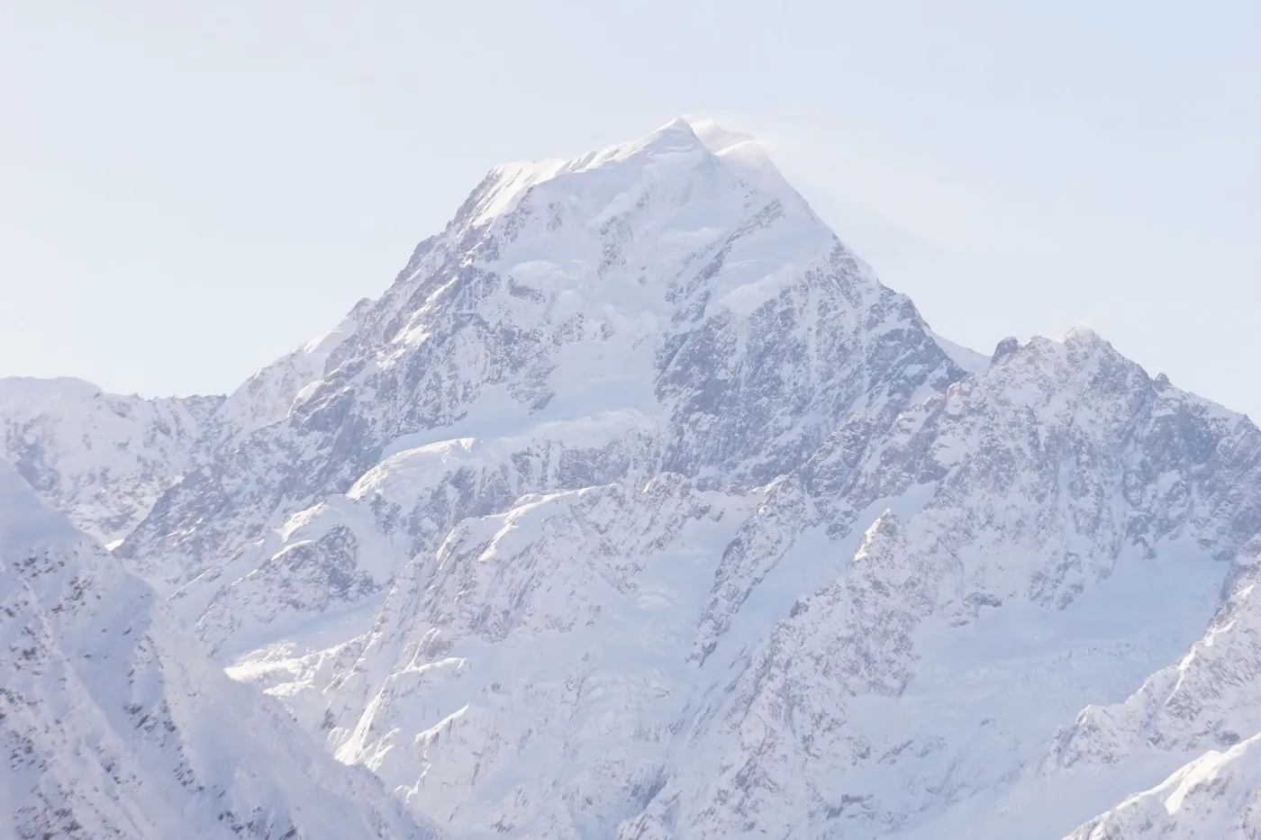 La cumbre nevada del Aoraki/Mount Cook y sus crestas en invierno, con un cielo pálido y neblinoso